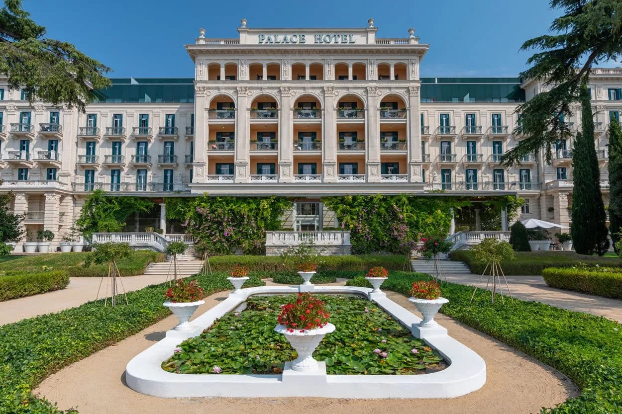 Palace Hotel exterior with formal gardens, lily pond, and manicured hedges in Slovenia
