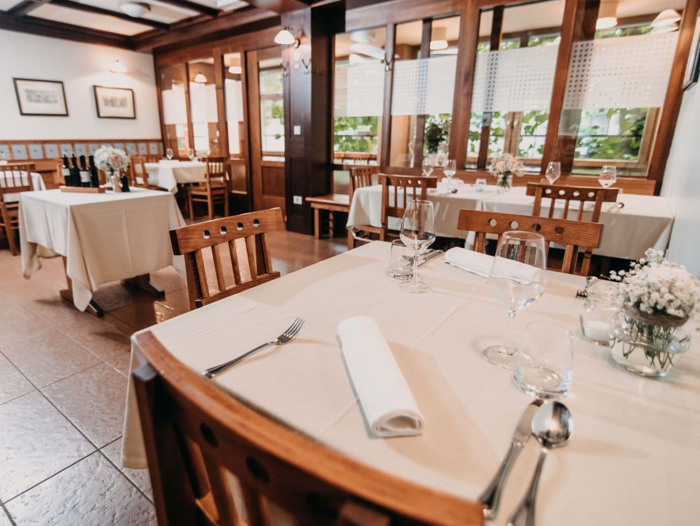 Dining room interior of Dvor Jezeršek gostilna with set tables and wooden chairs.