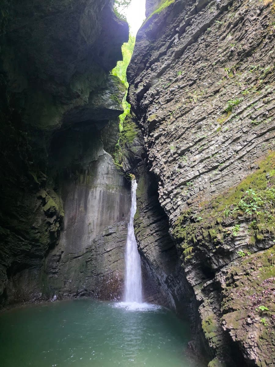 Waterfall flowing into a pool between steep rocky canyon walls