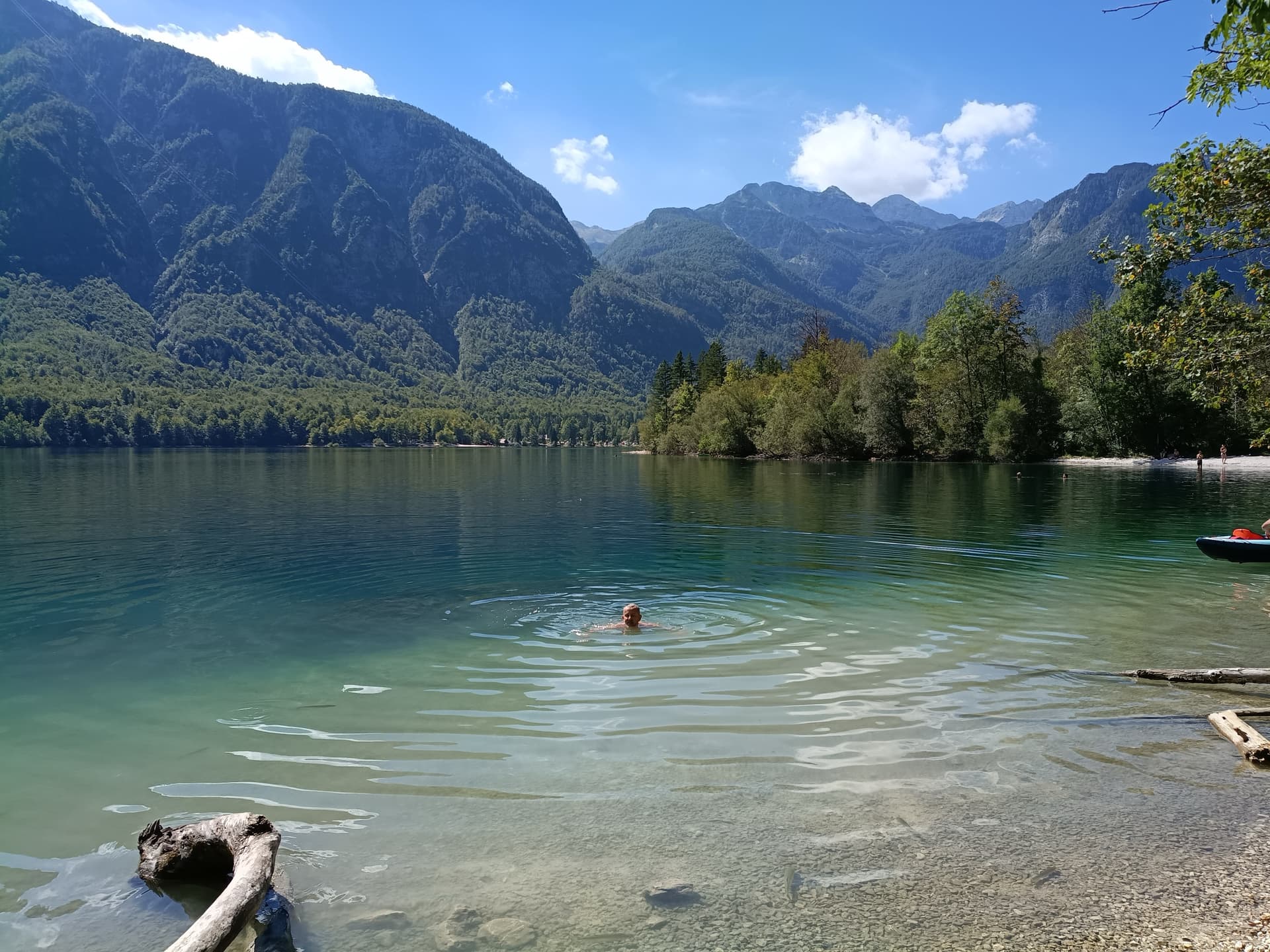 Person swimming in Lake Bohinj with surrounding mountains