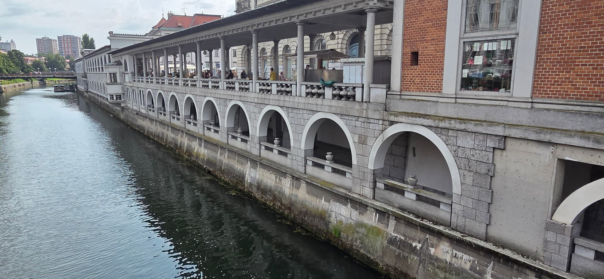 Ljubljana riverside colonnade and arched stone building along the riverbank