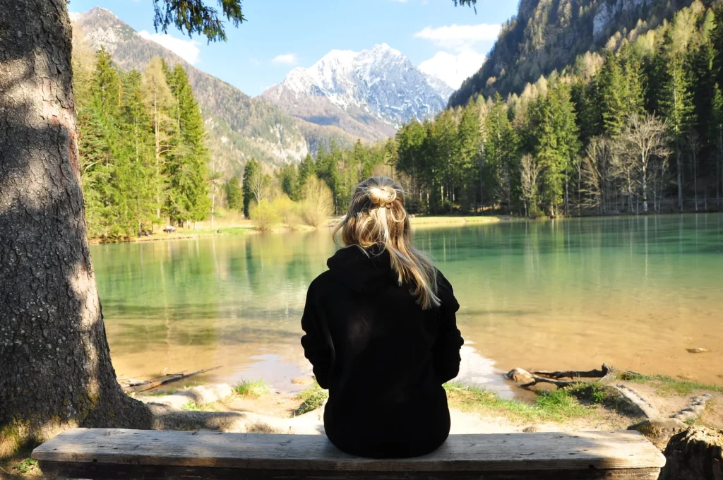 mädchen sitzend am rand des plansarsko jezero in slowenien skaliert