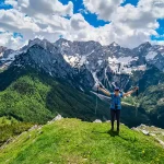 glückliche frau breitet ihre arme aus vor freude auf dem gipfel des goli vrh mit malerischem blick auf das gebirge kamnik savinja alpen erklommen